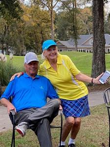 An image of two people smiling together on a golf course.